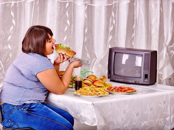 Женщина ест у телевизора
